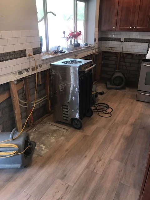 Kitchen remodel in progress with white subway tile backsplash, wood flooring, and stainless steel appliances