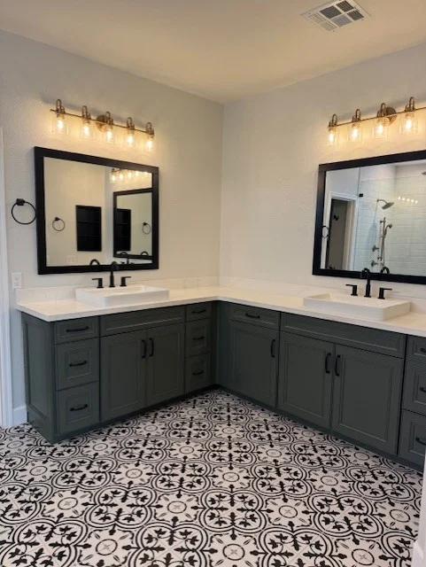 Master bathroom with dark cabinetry, white quartz counters, dual sinks, and patterned tile flooring