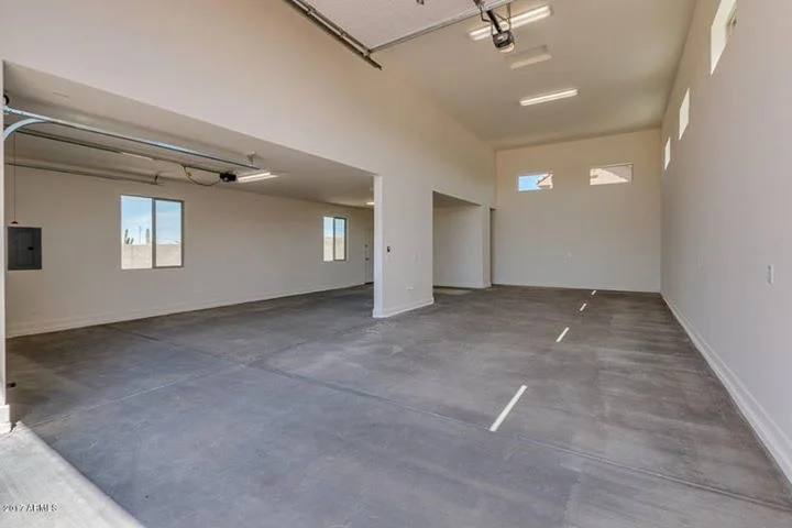 Empty garage interior with concrete floor, white drywall walls, and recessed lighting