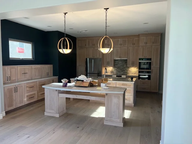 Kitchen remodel with wood cabinetry, island, stainless steel appliances, and pendant lights