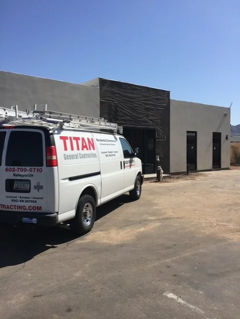 Commercial building with new concrete block walls, black metal overhead door, and entry doors under construction