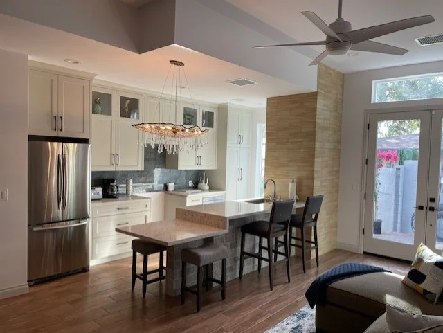 White kitchen cabinets, stainless steel appliances, quartz island, hardwood floors, and open dining area