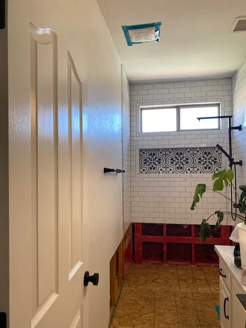 Bathroom with white subway tile walls, patterned tile accent, red floor tile, and updated fixtures