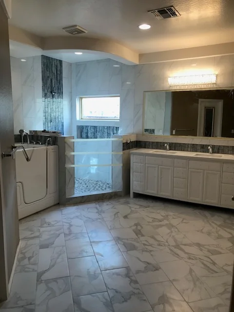 Master bathroom with marble tile floor, frameless glass shower, and custom vanity cabinetry