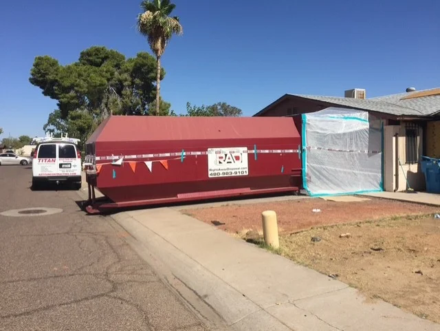 Red dumpster and plastic sheeting on residential home exterior during renovation
