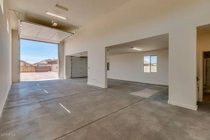 New garage interior with polished concrete floor, white walls, and overhead door opening