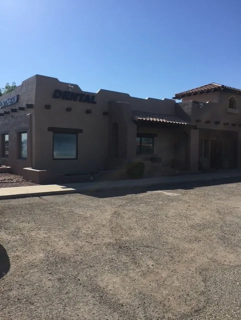 Dark brown stucco home with flat rooflines, contemporary windows, and wood beam portal entry