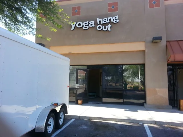 Commercial storefront with stucco facade, white signage, glass doors, and decorative tile details