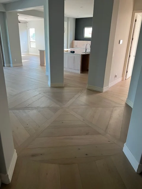 Herringbone hardwood flooring in open-concept interior with white kitchen cabinets and gray accent walls